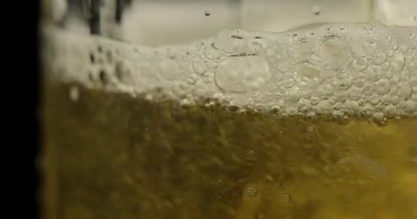 Versare birra fredda e dorata in un bicchiere. Birra artigianale facendo bolle e schiuma — Video Stock