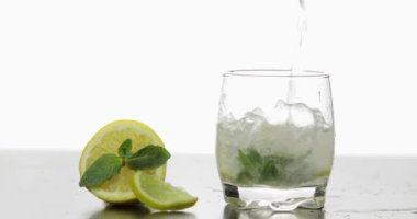 Bir bardak nane, limon, limon ve buz küpleri yaprakları ile soğuk bir içecek dökün