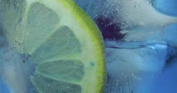 Cansado em um copo com bebida fria, limão, limão, groselhas, gelo. Close-up — Vídeo de Stock