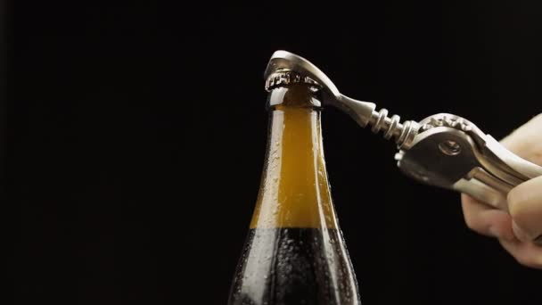 ビールの冷たいボトルをボトルオープナーで開きます。凝縮物と水滴 — ストック動画