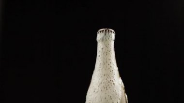 Adam bir şişe bira sallar. Bira kapağın altında köpük rom ile dökmeye başlar