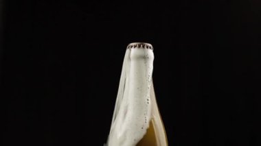 Adam bir şişe bira sallar. Bira kapağın altında köpük rom ile dökmeye başlar