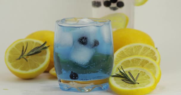 Додавання гілки розмарину в склянку з содовою лимонад синім коктейлем — стокове відео