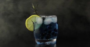 Soda limonata mavi kokteyl ile bir bardak siyah kuş üzümü ekleme
