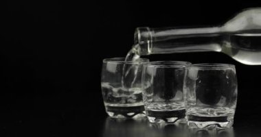Bir şişeden bardağa üç bardak votka döküyorum. Siyah arka plan