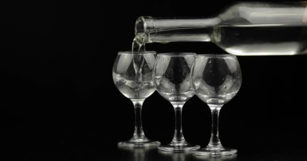 Drei Schuss Wodka aus einer Flasche in Glas gießen. schwarzer Hintergrund — Stockvideo
