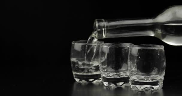 Öntött fel három lövés a vodka egy üveg üvegre. Fekete háttér — Stock videók