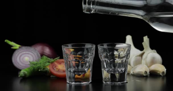 Häll alkohol vodka från en flaska i två sköt glas. Bakgrund med grönsaker — Stockvideo