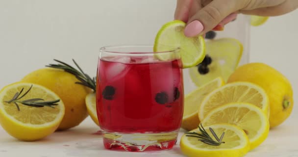 Hozzáadása citromos szelet egy pohár szénsavas limonádé piros koktél — Stock videók
