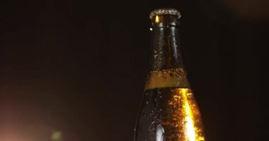 Siyah bir arka plan üzerinde soğuk bira şişesi. Yavaşça dönüyor. Kondens