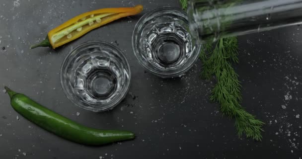 Giet alcohol drinken wodka uit een fles in twee shot glas. Oppervlak met snacks — Stockvideo