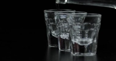 Bir şişeden bardağa üç bardak votka döküyorum. Siyah arka plan