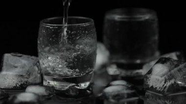 Şişeden bardağa bir bardak votka döküyorum. Siyah arka plan