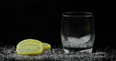 Buzlu viski. Siyah arka planda şişeden viski romu dökülüyor.