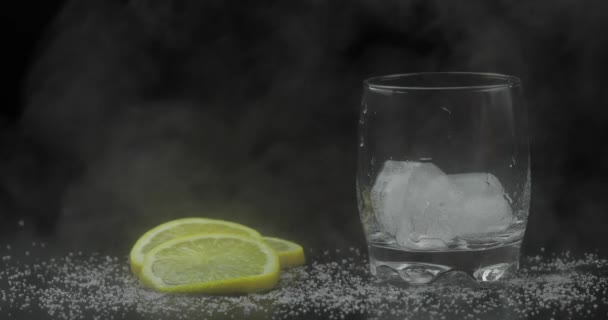 Whiskey with ice. Pouring whisky rum from the bottle on black background — Stock Video