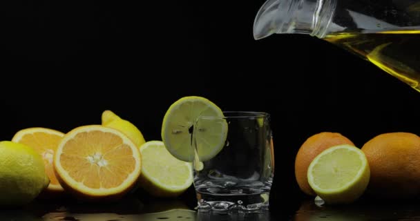 Вылить сок из кувшина в стекло, апельсин и лимон ломтики на заднем плане — стоковое видео
