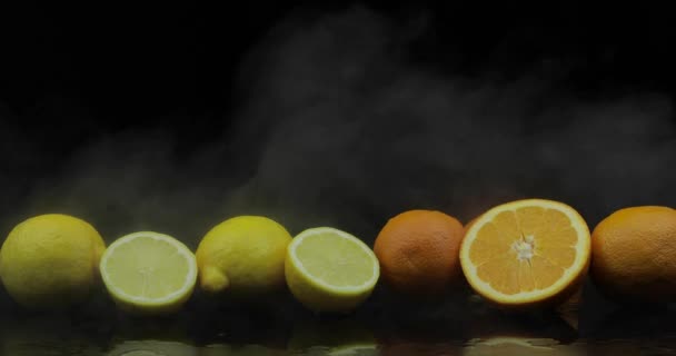 Limón tropical y naranja en heladas nubes de humo de niebla sobre fondo negro — Vídeo de stock