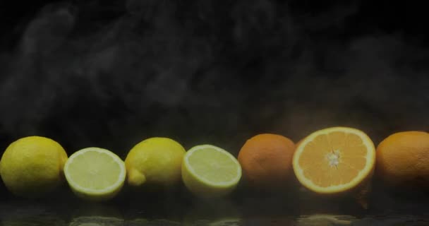 Limón tropical y naranja en heladas nubes de humo de niebla sobre fondo negro — Vídeo de stock