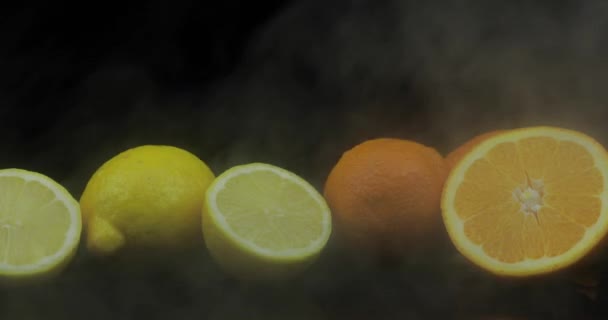 Limón tropical y naranja en heladas nubes de humo de niebla sobre fondo negro — Vídeo de stock