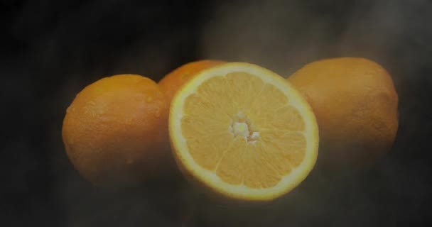 Fruta tropical naranja en hielo frío nubes de humo de niebla sobre fondo negro — Vídeos de Stock