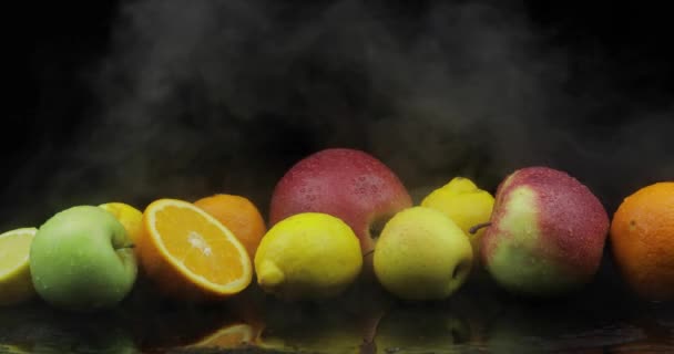 Limão tropical, laranja, maçã em nuvens de gelo frias de fumaça de nevoeiro no fundo escuro — Vídeo de Stock