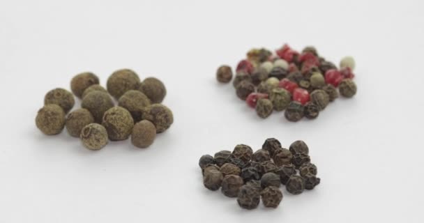 Blandning av mångfärgad peppar rotation. Ärter med kryddor. Makro på vit bakgrund — Stockvideo