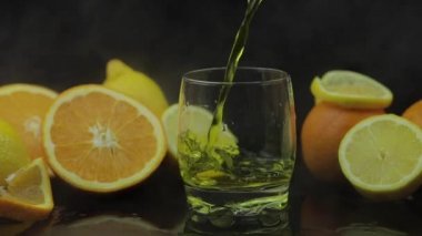 Arka planda cam, portakal ve limon dilimleri içine suyu dökün. Yavaş çekim