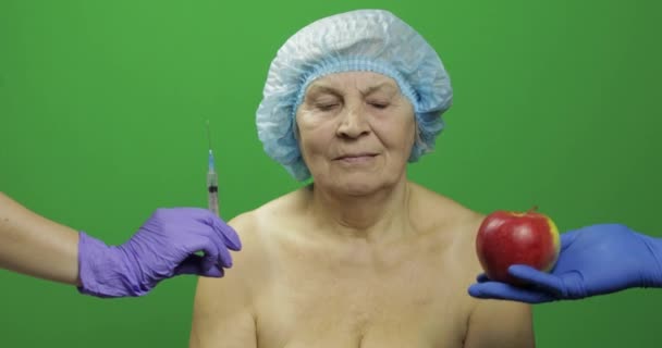 Donna anziana in cappello protettivo sceglie tratta farmaci o frutta — Video Stock