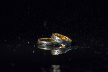 Karanlık yüzeyde ışıkla parlayan alyanslar. Su sıçramaları