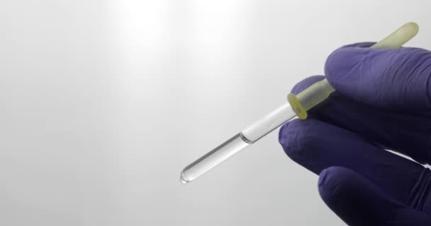 Main dans le gant médical goutte à goutte de la pipette. Vidéo en gros plan. Goutte liquide — Video