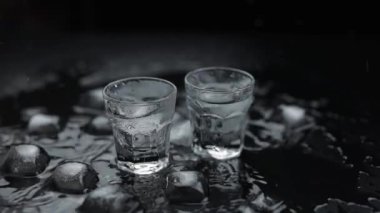 Siyah arka plan karşı cam votka atış için buz küpleri ekleyin. Alkollü içki