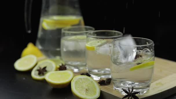 Προσθέτουμε παγάκια σε χυμό λεμονιού σε γυαλί με φέτες λεμονιού. Αλκοολούχα κοκτέιλ — Αρχείο Βίντεο