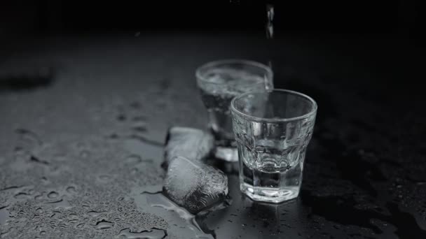 Het gieten van shots van wodka in glas. Zwarte achtergrond. Storten van alcohol drank — Stockvideo