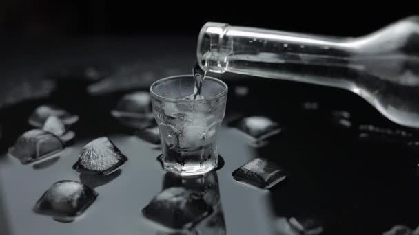 A despejar uma dose de vodka em vidro. Fundo preto. Despeje de bebida alcoólica — Vídeo de Stock