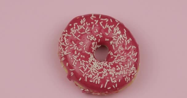 甜甜甜圈在粉色背景上旋转。顶部视图。美味的，新鲜的，洒满了甜甜圈 — 图库视频影像
