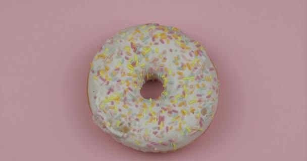 Rosquilla dulce girando sobre fondo rosa. Vista superior. Sabroso, donut recién espolvoreada — Vídeo de stock