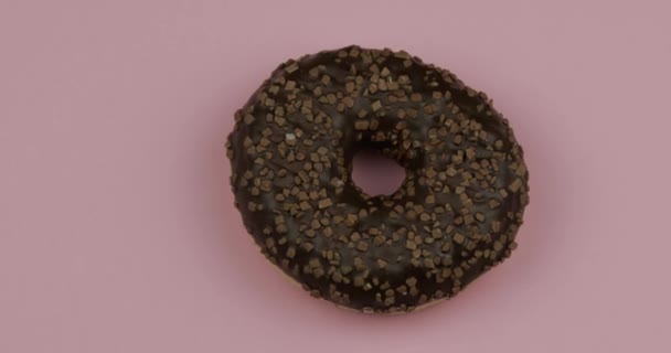 분홍색 배경 위에서 회전하는 도넛이야. 위에서 본 모습. 맛있고 신선 한 도넛 — 비디오