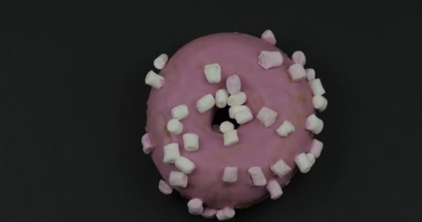 甜甜甜圈在黑色背景上旋转。顶部视图。美味，新鲜的甜甜圈 — 图库视频影像