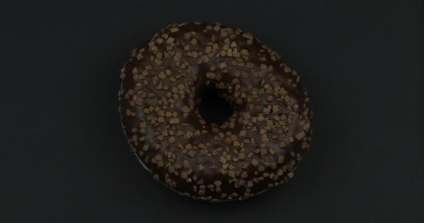 Солодкий пончик, що обертається на чорному тлі. Вид зверху. Смачний, свіжий посипаний пончик — стокове відео