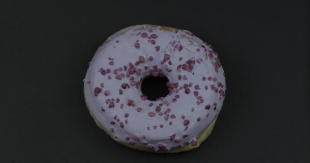 Doce donut girando sobre fundo preto. Vista superior. Saboroso, donut polvilhado fresco — Vídeo de Stock