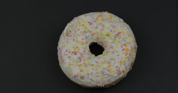 Süßer Donut auf schwarzem Hintergrund. Ansicht von oben. leckerer, frisch bestreuter Donut — Stockvideo