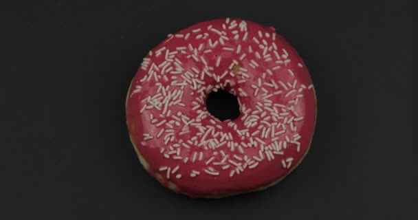 Süßer Donut auf schwarzem Hintergrund. Ansicht von oben. leckerer, frisch bestreuter Donut — Stockvideo