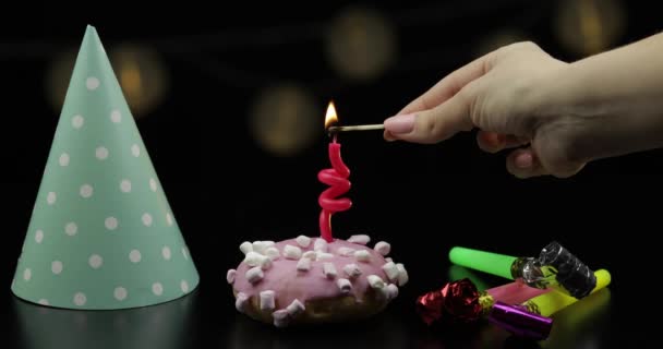 Fiesta. Rosado donut y una vela festiva roja en él. Caída de confeti dorado — Vídeos de Stock