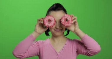 Mutlu güzel genç kız poz ve çörekler ile eğleniyor. Renk anahtarı