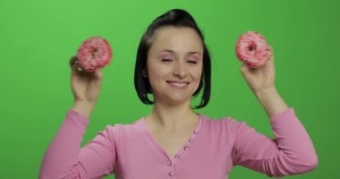 Mutlu güzel genç kız poz ve çörekler ile eğleniyor. Renk anahtarı