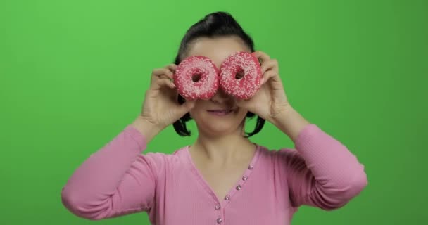 Ευτυχισμένο όμορφο νεαρό κορίτσι ποζάρει και να διασκεδάζουν με ντόνατς. Πλήκτρο αποχρώσεων — Αρχείο Βίντεο