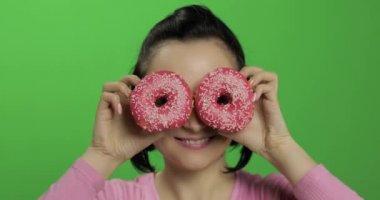 Mutlu güzel genç kız poz ve çörekler ile eğleniyor. Renk anahtarı