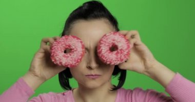 Mutlu güzel genç kız poz ve çörekler ile eğleniyor. Renk anahtarı