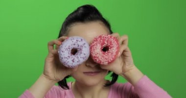 Mutlu güzel genç kız poz ve çörekler ile eğleniyor. Renk anahtarı