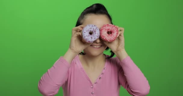 Glücklich schönes junges Mädchen posiert und Spaß mit Donuts hat. Chroma-Schlüssel — Stockvideo